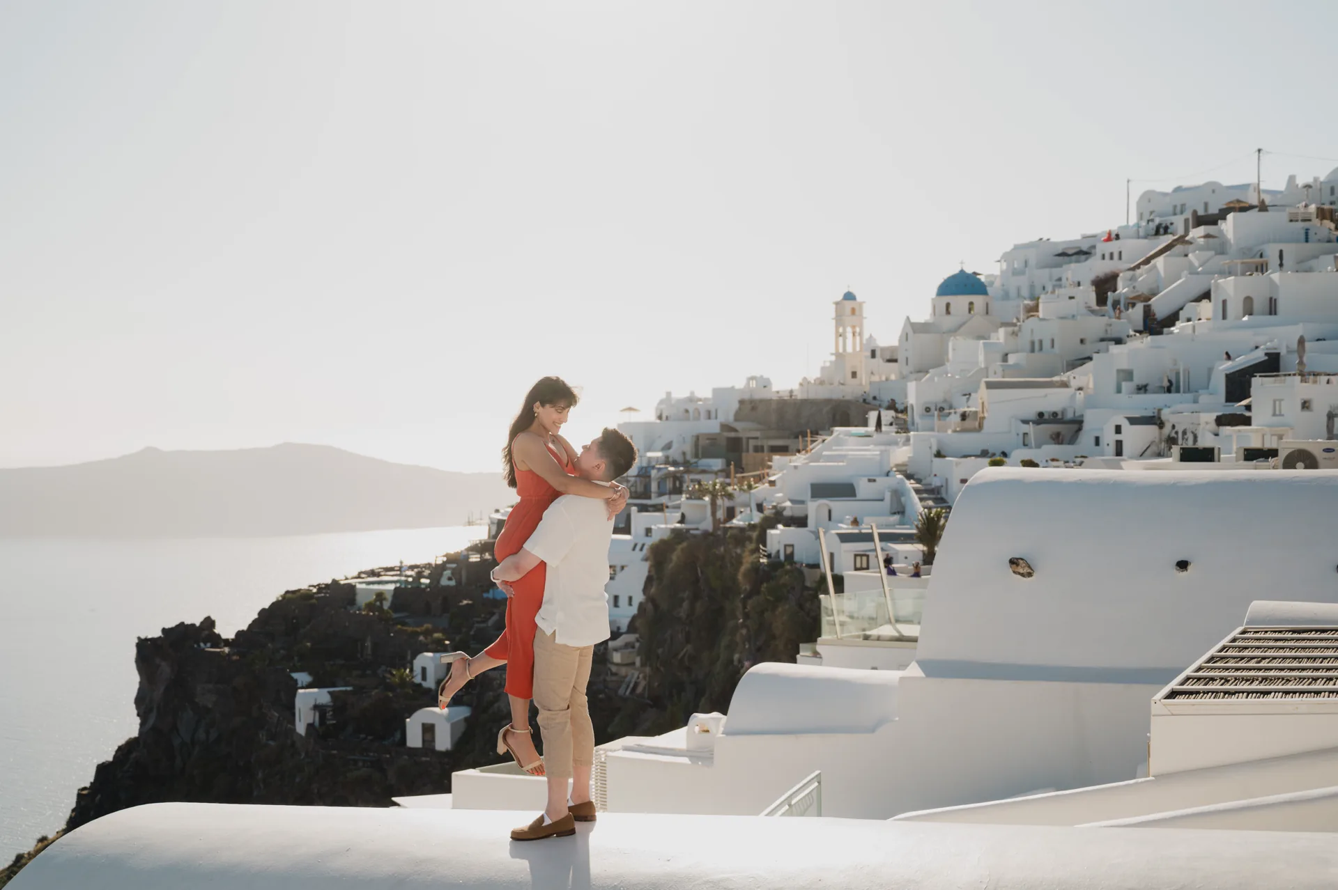 Fredrik lifting Erin above a sunlit whitewashed hillside